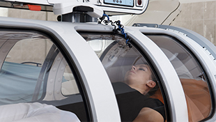A woman lies inside a hyperbaric chamber.