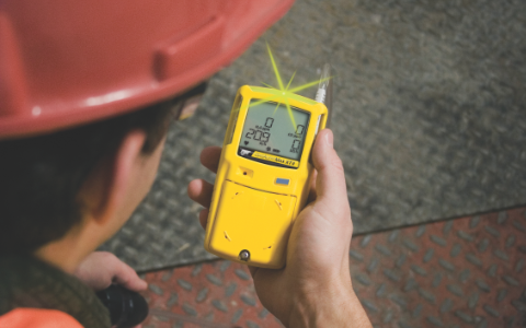 Mid-shot of a Honeywell BW Clip gas detector grasped in a worker’s hand.