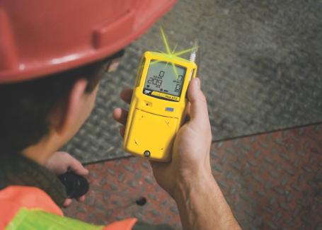 Mid-shot of a Honeywell BW Clip gas detector grasped in a worker’s hand.