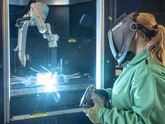 A welder is working a robotic welding arm.