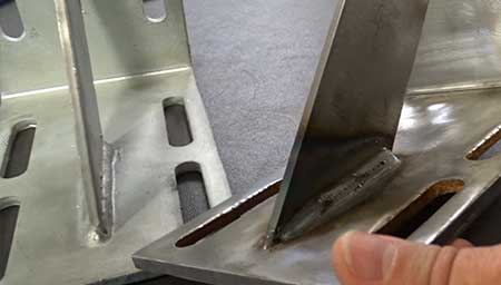 An Advanced Fabrication expert comparing the weld quality on two brackets.