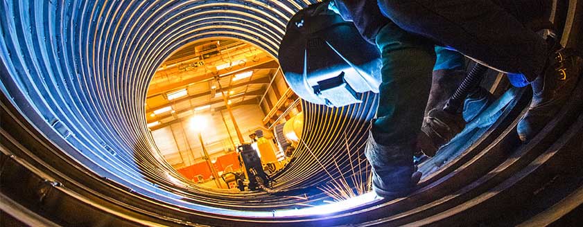 A welder working inside a large pipe