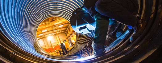 A welder working inside a large pipe