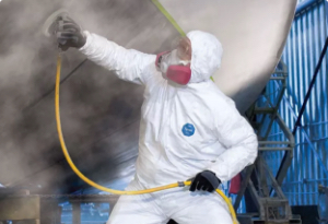 Worker is protected from hose spray by wearing white DuPont protective gear.