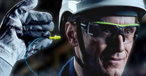 A worker with protective 3M eye and head gear and gloves places an earplug into his ear.