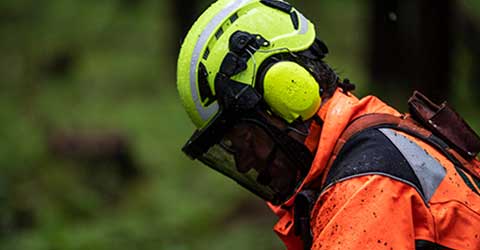 A worker with protective ear, face and head gear looks down at the job.