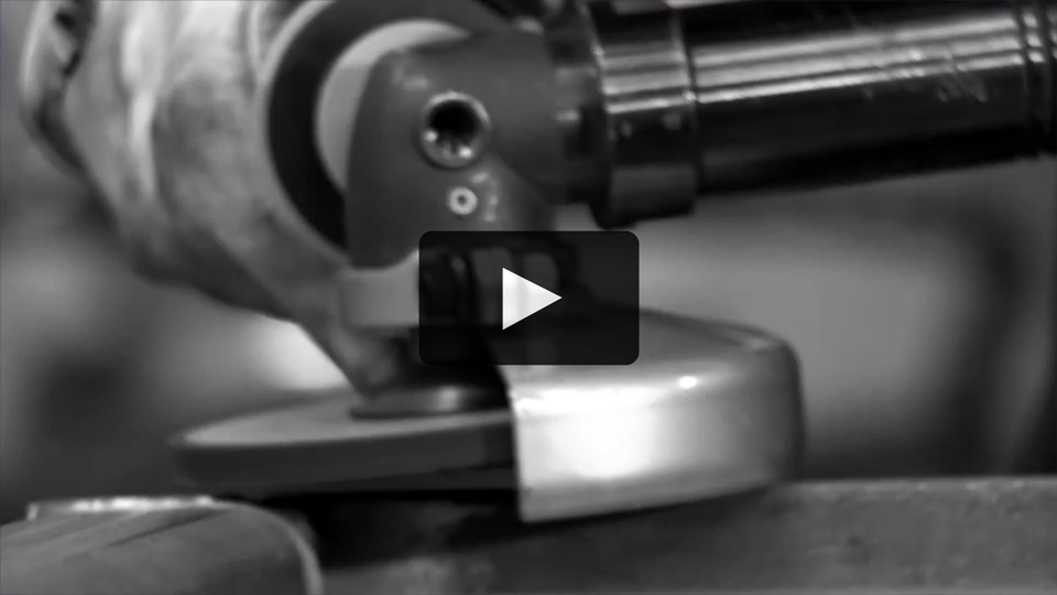 Black and white, close-up photo of a grinding disk about to touch metal.