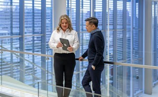 Two professionals leaning against a railing in a medical facility