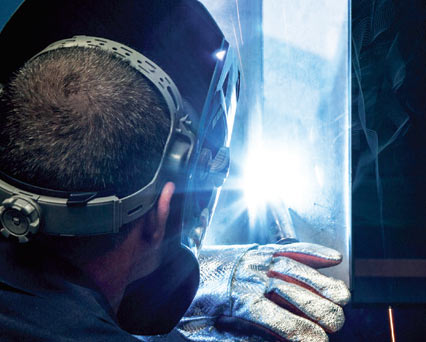 Welder, wearing welding helmet & welding gloves, MIG/GMAW welding stainless steel with ARCAL Chrome shielding gas.