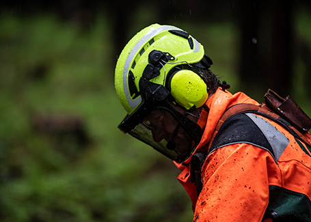 A worker with protective ear, face and head gear looks down at the job.