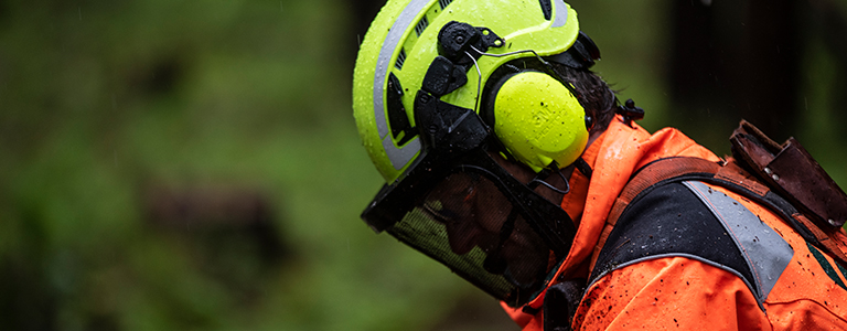 A worker with protective ear, face and head gear looks down at the job.