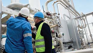 Two people inspecting part of an installation for FLOXAL™ on-site nitrogen gas generation for food production and processing.