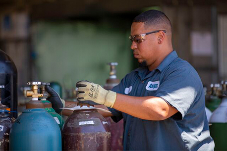 An Airgas technician safety handles a packaged gas cylinder.