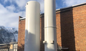 Two liquid nitrogen bulk tanks on the side of a brick building.